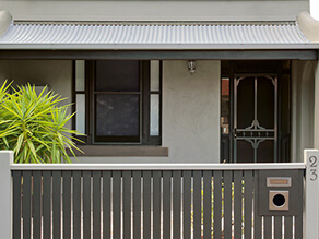 Front Exterior with Dark Grey Fence and Light Green Walls and Tree in Front GArden